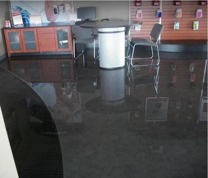 standing water in store; merchandise hanging on wall; table and chair for customers