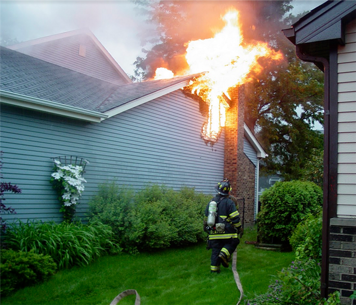 a fireman running with a hose to put out a fire on someones roof