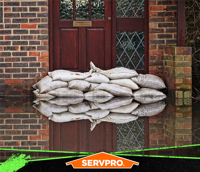 A pile of sandbags in front of the door of a flooded yard of a home